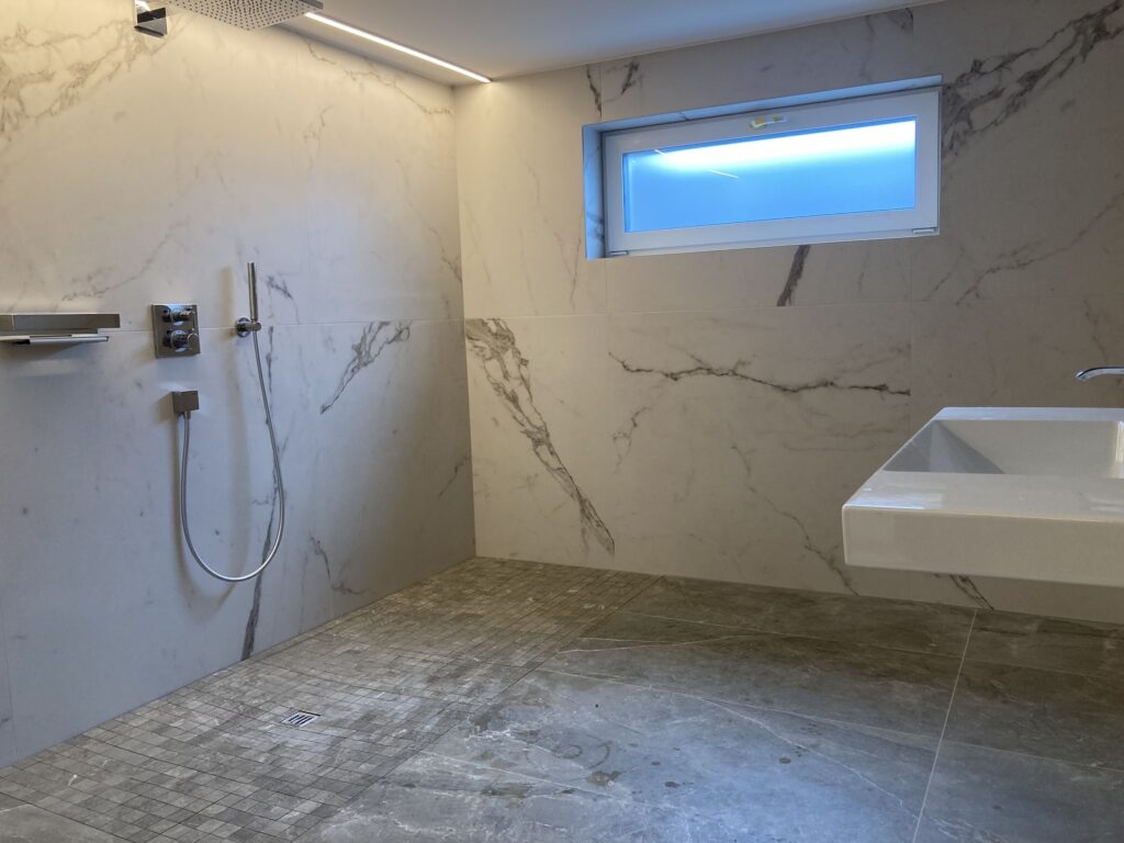 Bodengleiche, barrierefreie Dusche mit Großformatfliesen in Marmoroptik